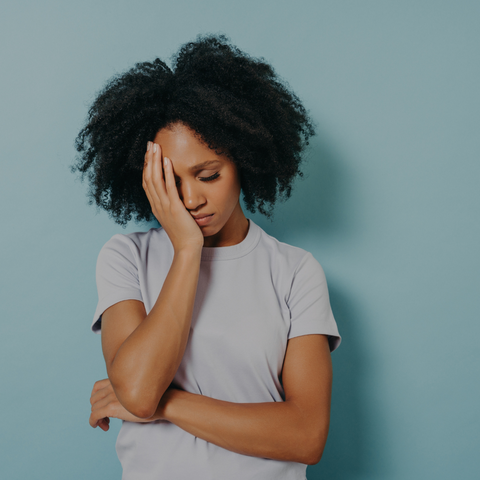 woman feeling stressed with one arm crossed and the other arm on her face