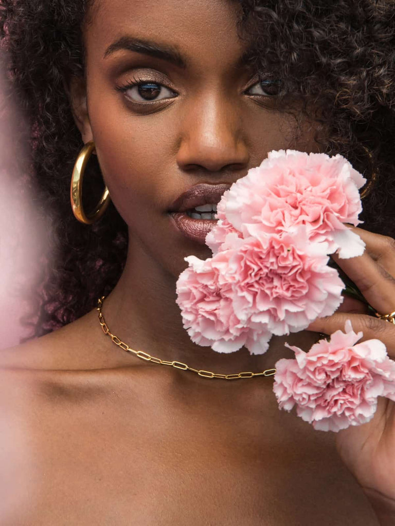 Woman wearing Valentine’s Day gold jewelry necklace holding flowers