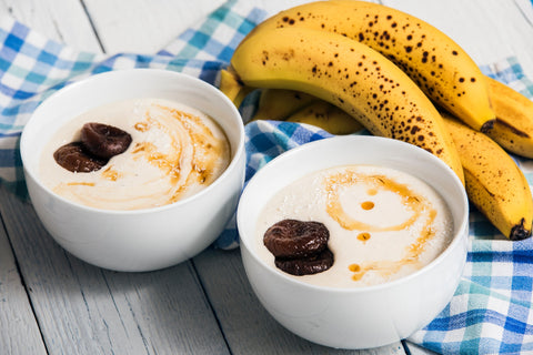 Two bowls of yogurt and bananas on a table