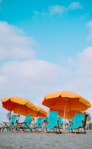 Orange umbrellas with green sun chairs on sandy beaches 