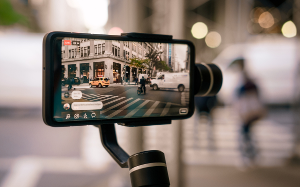 Smartphone on gimbal capturing a busy city street.