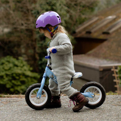 En pige lærer at cykle om efteråret i et par efterårsstøvler til børn.