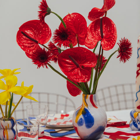 modern red floral arrangement in misette primary confetti glass vase