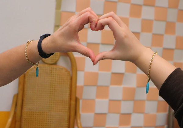 Attendees making a heart wearing their handmade charm bracelets.