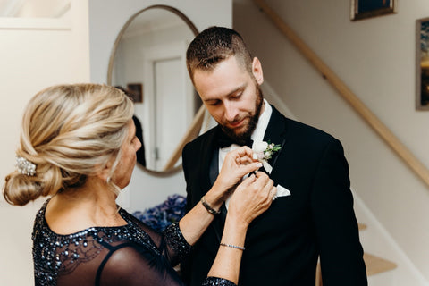 Image of the mother of the groom adjusting groom's lapel on wedding day