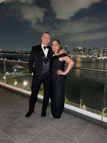 Couple at formal nighttime event outside in black tie wear with city in background