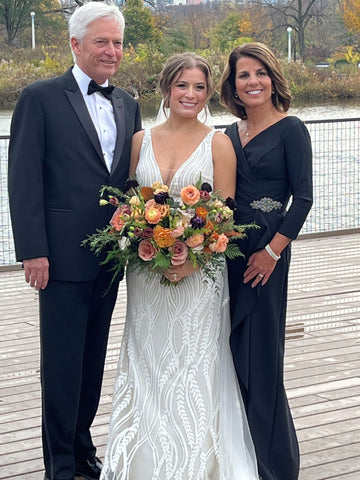 Image of a bride with her parents in elegant evening wear outdoors on wedding day