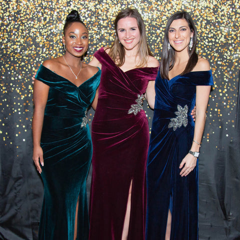 Image of three women in festive velvet evening gowns enjoying a special occasion