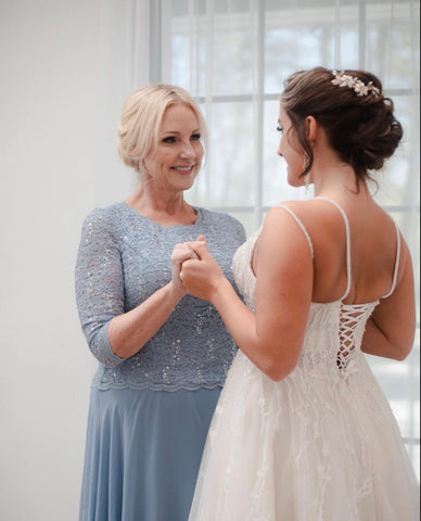 Mother of the bride and bride holding hands smiling