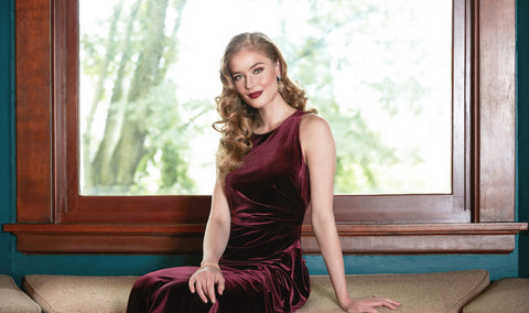 Image of woman sitting down in velvet red dress