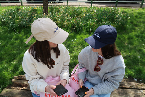 Two women wearing Bonne Aventure sweatshirts and caps