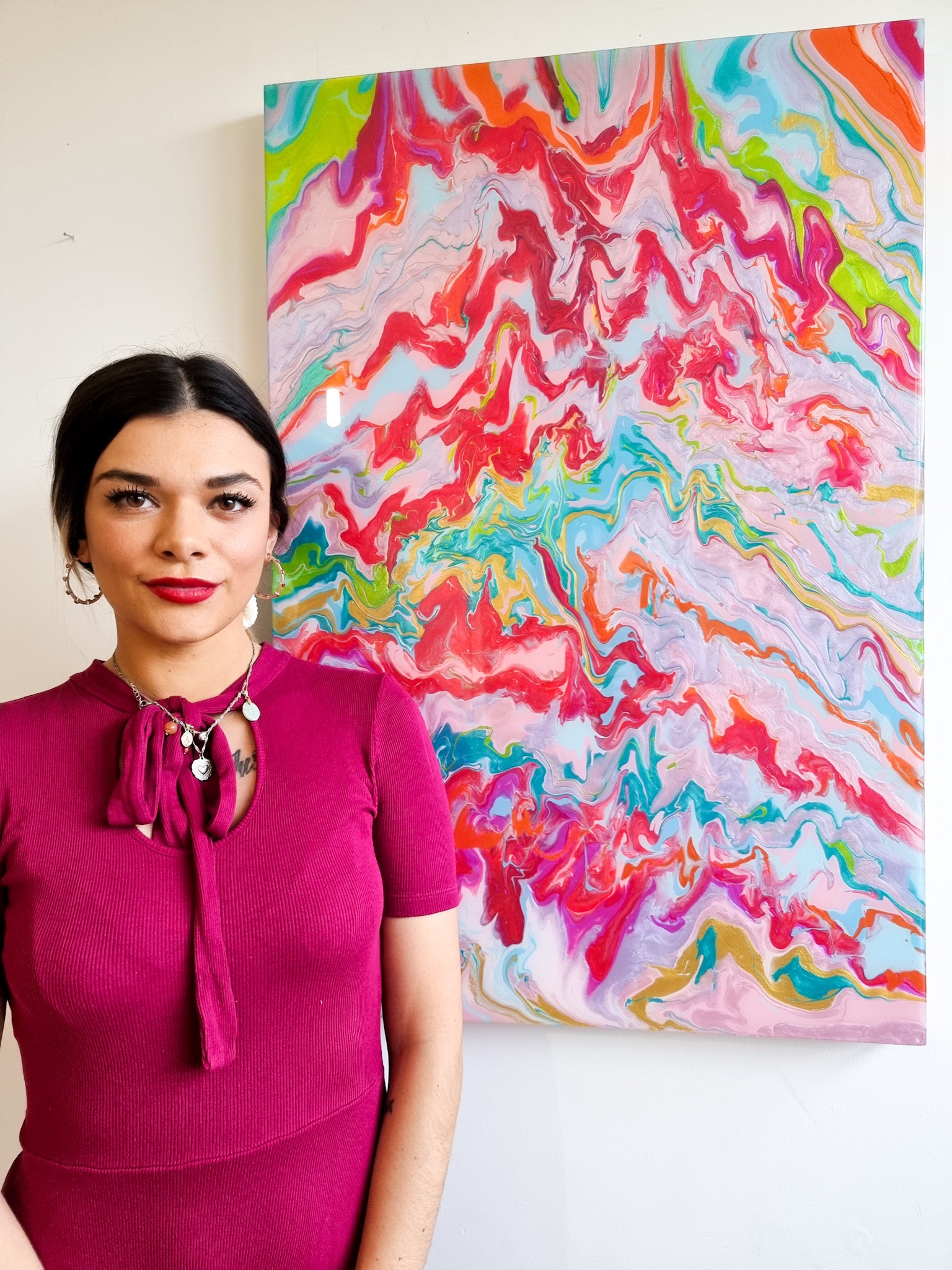 Female artist standing next to abstract pink painting