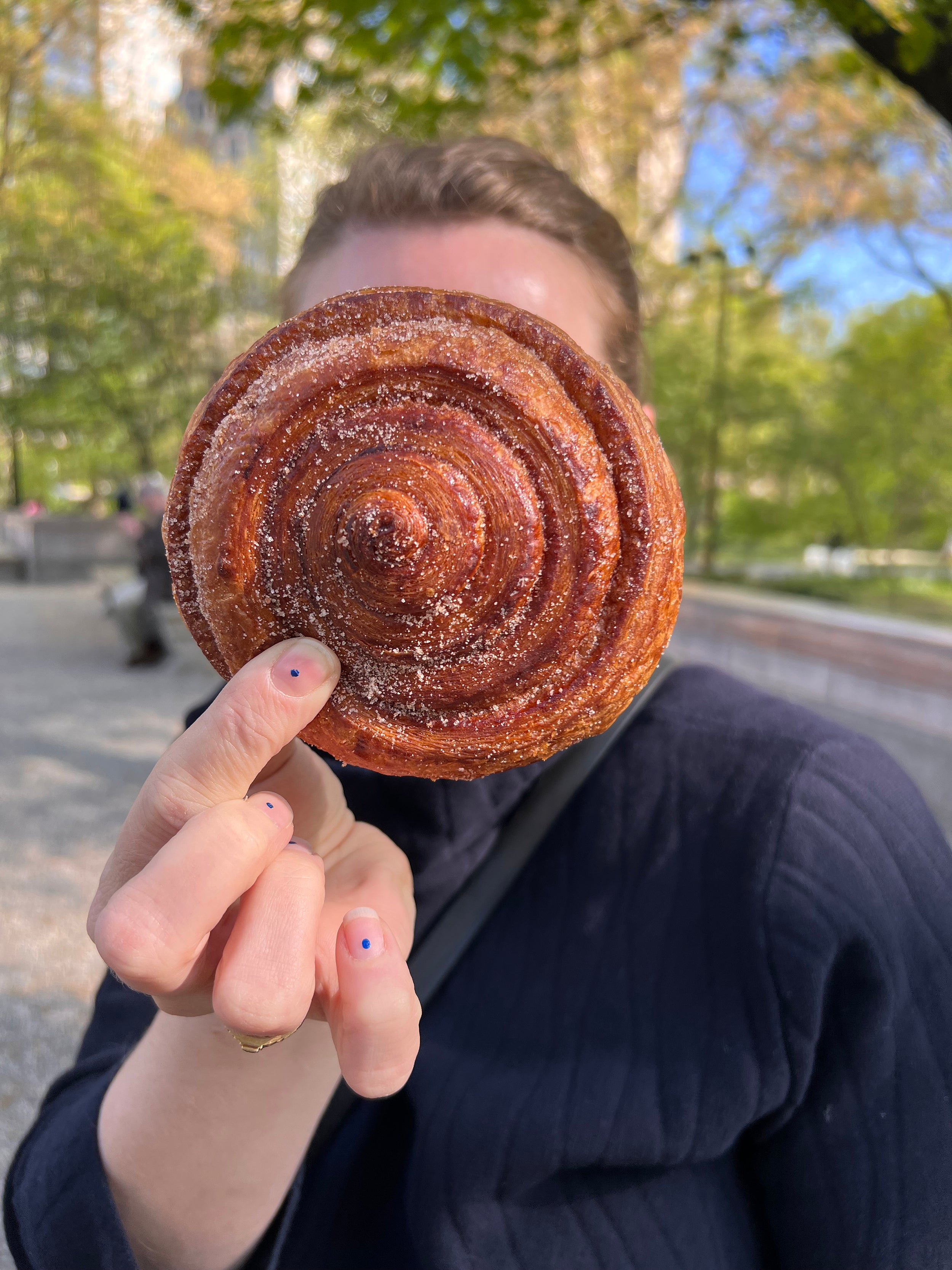 Emily holding a cinnamon roll in front of her face.