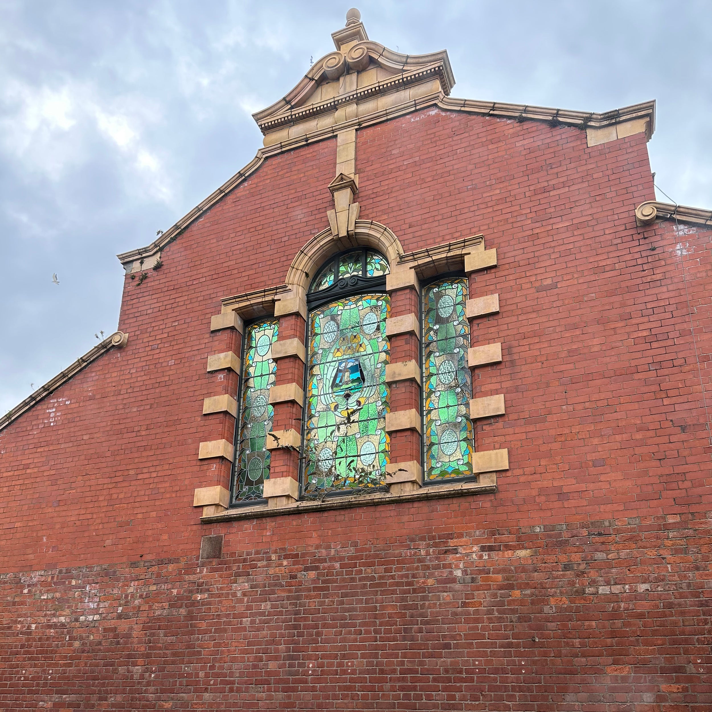 A stained glass window in the red bricked building from the outside