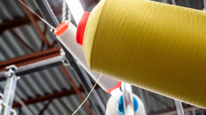 A closeup shot of a yellow yarn cone in the mill