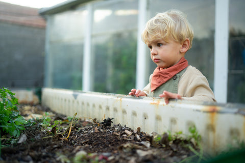 Bambino accanto al compost all'aperto nel giardino