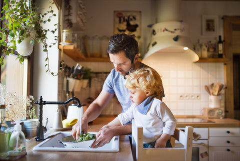 Giovane padre con bambino che cucina verdure