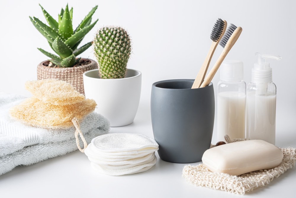 Zero waste, sustainable bathroom and lifestyle. Bamboo toothbrush, natural soap bar, loofah sponge, cotton pads, homemade DIY beauty products in reusable bottles.