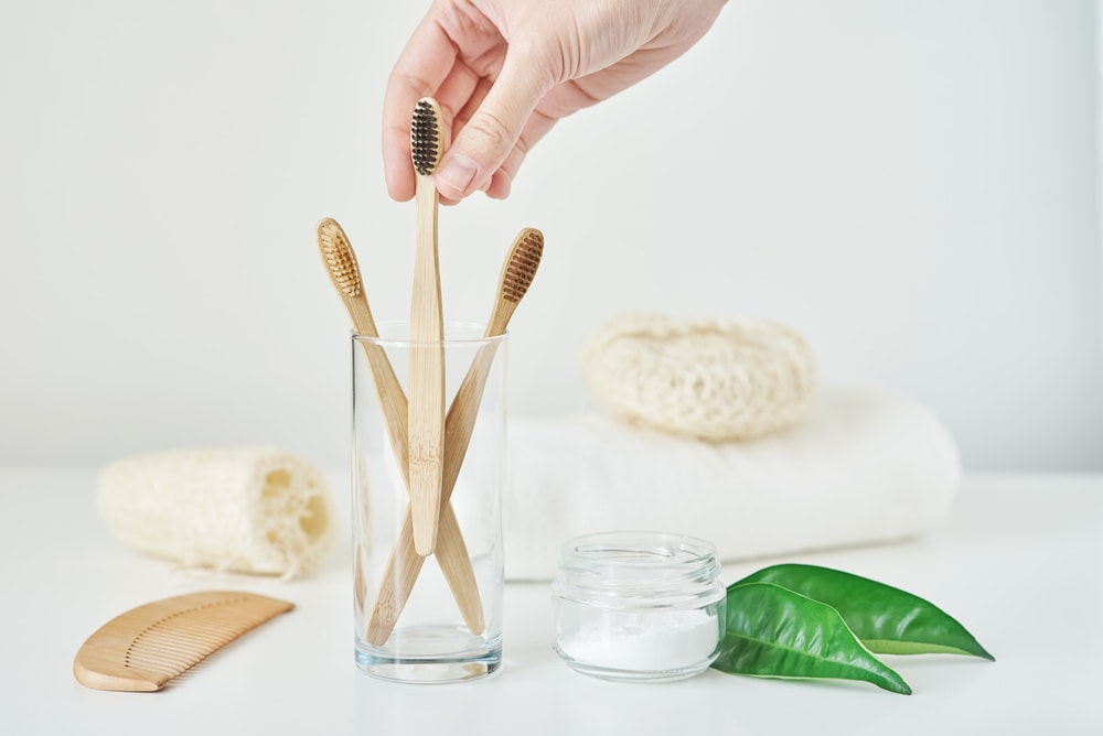 No plastic zero waste concept. Eco friendly toothbrushes in glass, towel, tooth powder and washcloth on a white background.