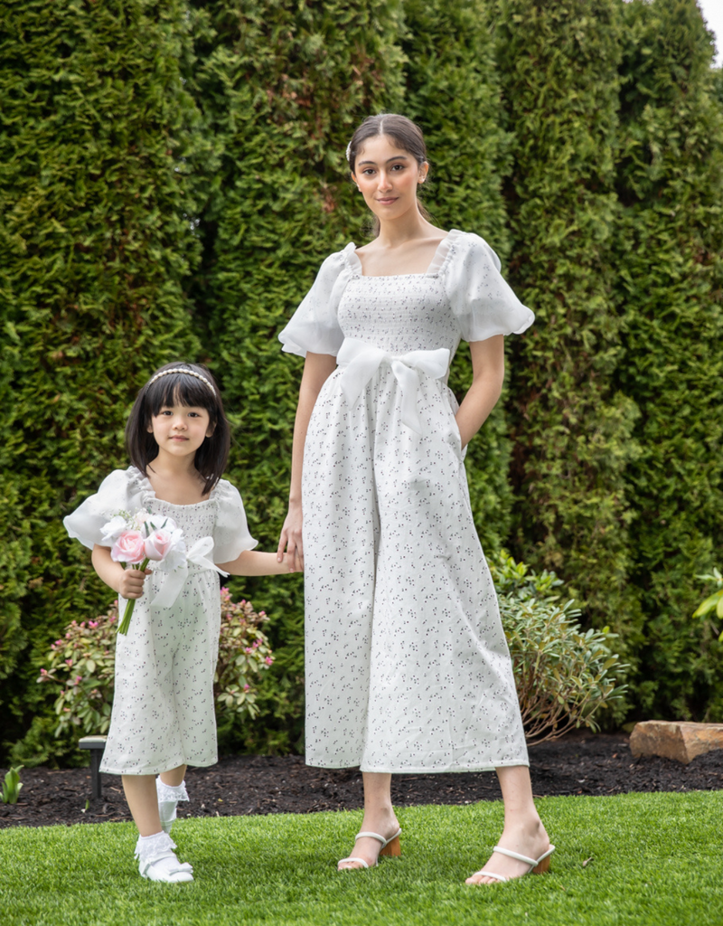 Mom and little girl posing in the garden wearing their matching mommy and me white jumpsuits nursing-friendly