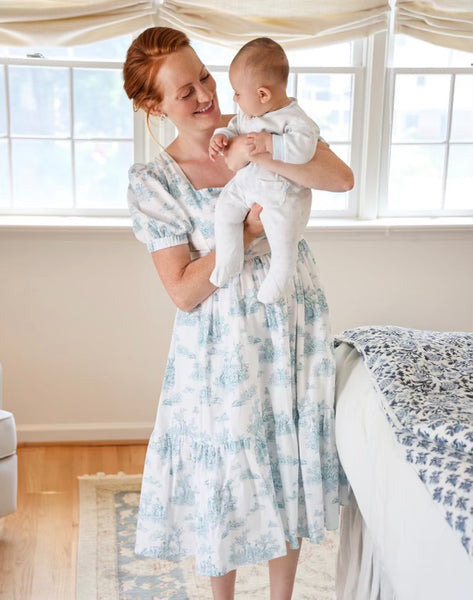 Therese wearing a Lan midi dress with nursing zippers in Blue La Mere Toile while carrying her little boy in her arms and looking him sweetly in his eyes