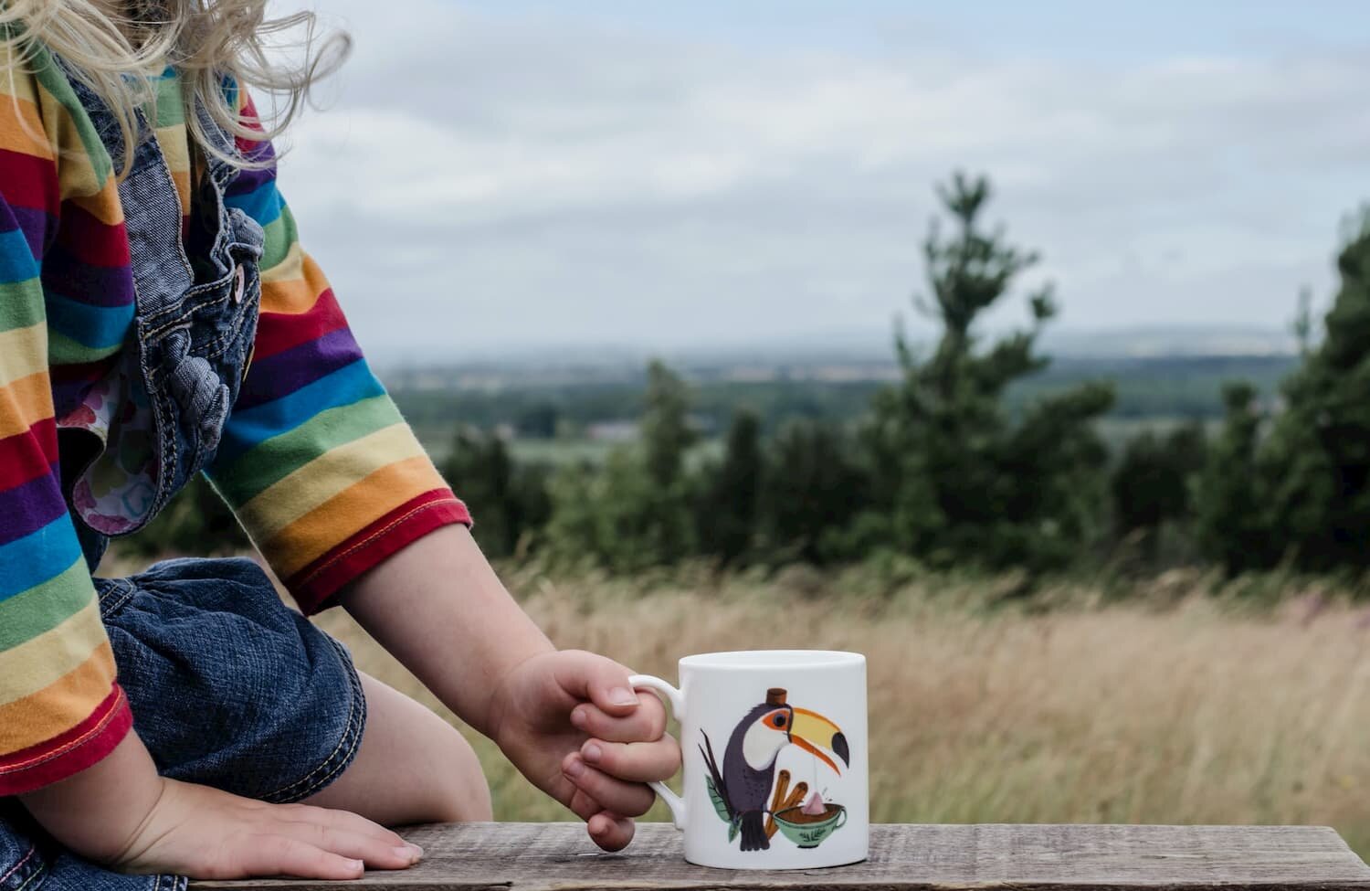 girl sitting on wall holding a mug of tea