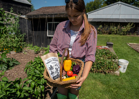 Woman holding basket of vegetables and worm manure