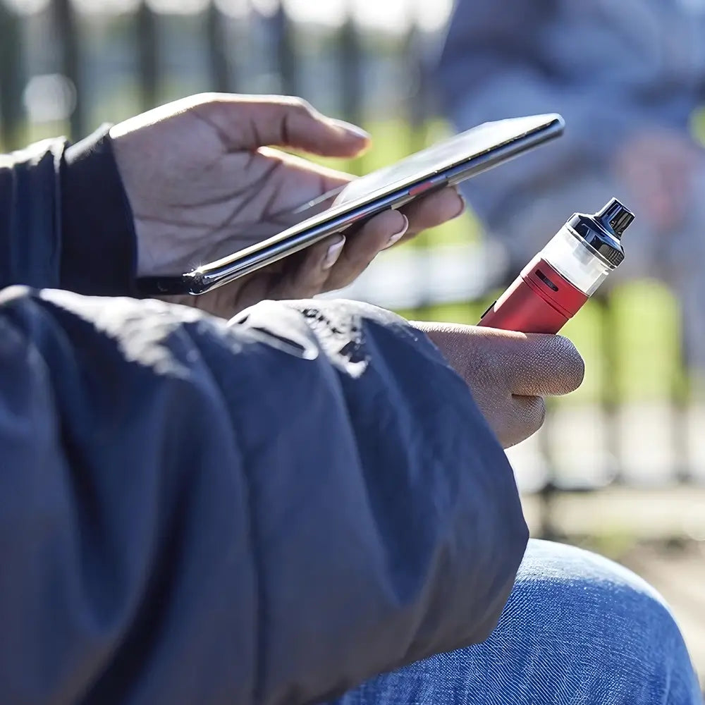 Youth smoking disposable vape in a park