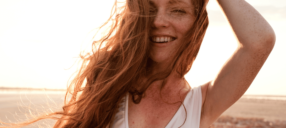 woman with long red hair running fingers through it