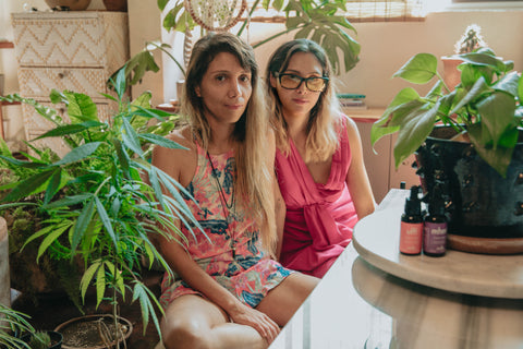 Mariana and Diana sit among plants in their living room
