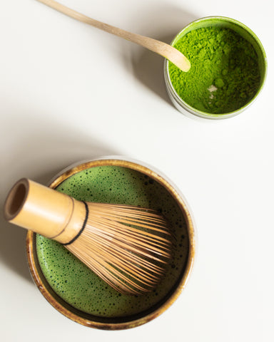 ceramic matcha bowl with matcha whisk and a small tin of matcha powder