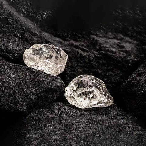 [Der „X-Faktor“ für Blutdiamanten: ungeschliffene Diamanten auf dunklen, strukturierten Steinen. Sie haben eine natürliche, unregelmäßige Form und zeigen vor dem kontrastierenden schwarzen Hintergrund ein klares, kristallines Aussehen.] -[Ouros-Juwelen]