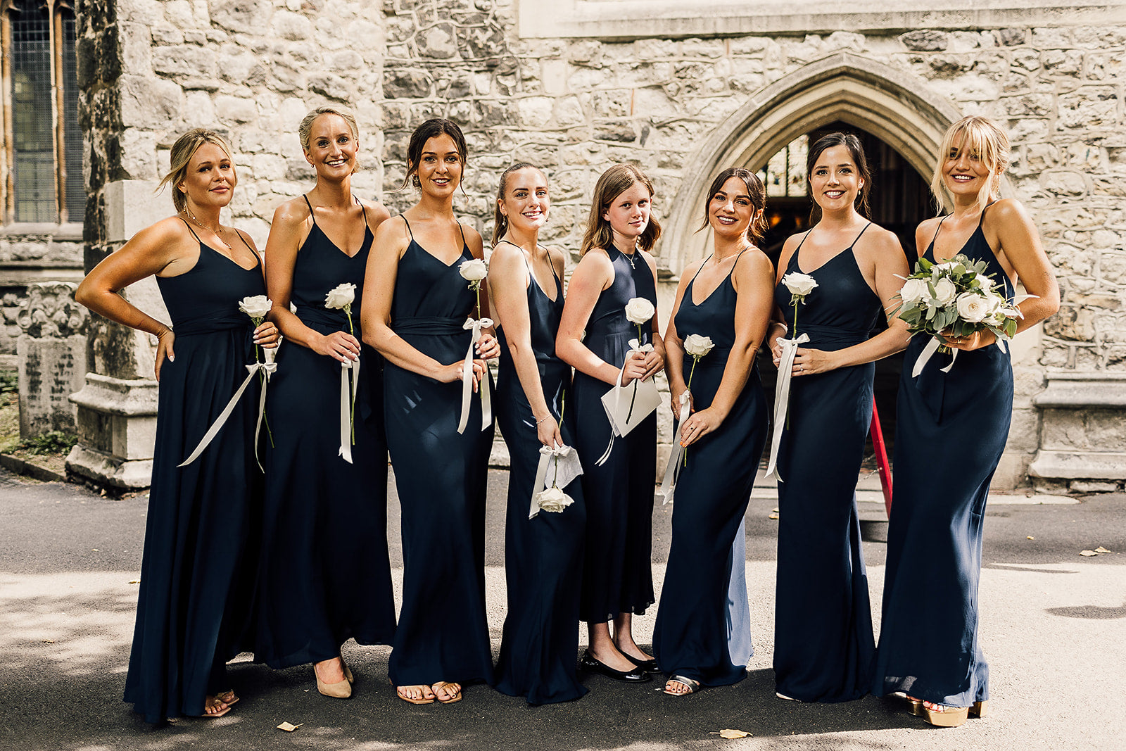 Eight bridesmaids in navy blue bridesmaids dresses.