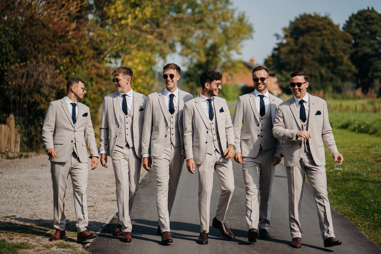 Groom and groomsmen wearing matching dark navy blue ties and pocket squares to the bridesmaids.