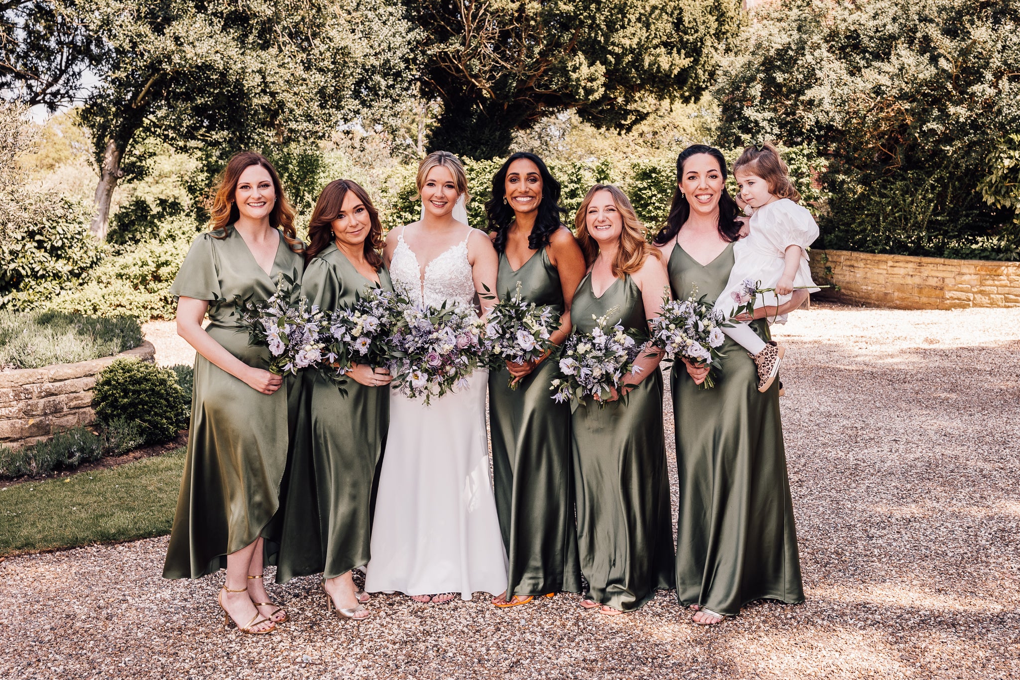 Six girls standing outside Stanlake Park Vineyard wedding venue in Twyford, five bridesmaids wearing green satin bridesmaids dresses and one bride wearing a white wedding dress.