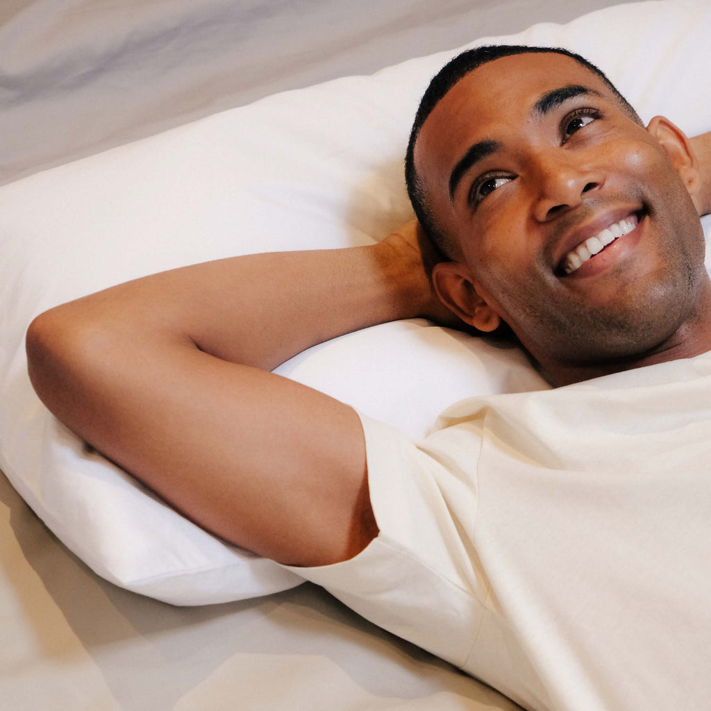 一个男人微笑着躺在一个睡眠云核心羽绒枕头