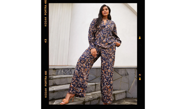 Pictured: Model standing on stairs posing for the camera. She is wearing Capitano printed navy pants and the matching Capitano printed long sleeve top.