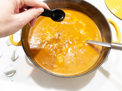 agregando sopa de calabaza y agave en una olla holandesa de caléndula de hierro fundido de 5 cuartos