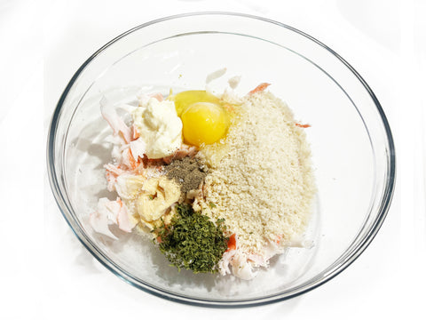 agregar huevo y especias a la mezcla de pastel de cangrejo en un tazón