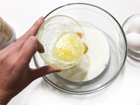 agregar mantequilla a los huevos y la leche para hacer panqueques de piedra en una plancha chantal