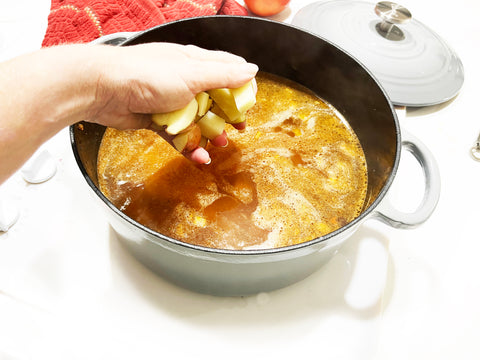 adding potatoes to grey cast iron dutch oven