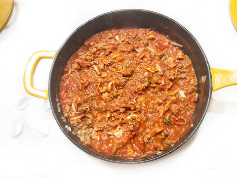 agregue el puré de tomate a la carne y revuelva en una sartén para saltear de hierro fundido de 4 cuartos