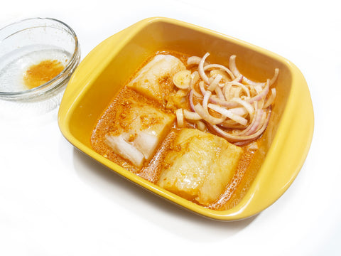 marinading fish in marigold ceramic bakeware with sliced onions