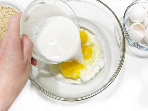 mixing eggs and milk to coat chicken milanese