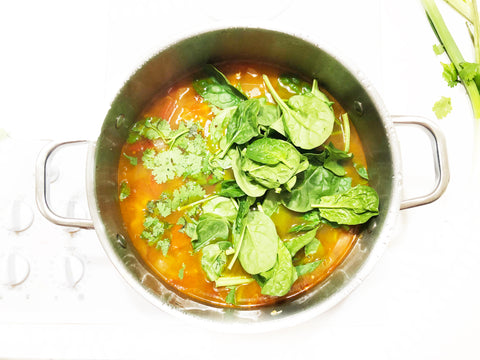 agregue espinacas y cilantro a la sopa posole en una olla de caldo de rayas de 6 cuartos
