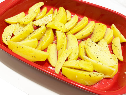 greek style lemon potatoes in ceramic rectangular baker before oven