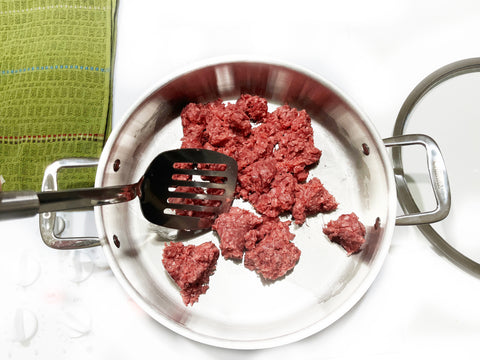 ground beef in 3 clad sauteuse with spatula