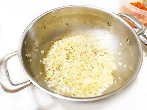 brown onions for summer risotto in chefs pan