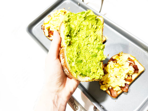 spreading avocado onto bread before putting on griddle
