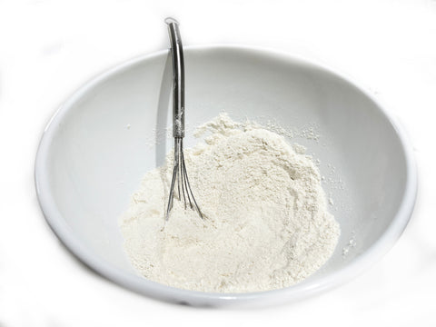 mixing flour and sugar in white bowl for blueberry bread